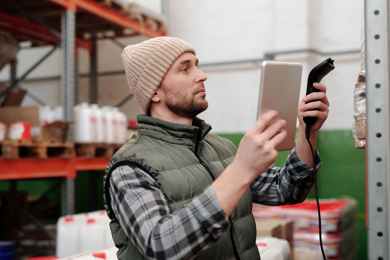 Warehouse team member checking stock against a tablet and barcode scanner